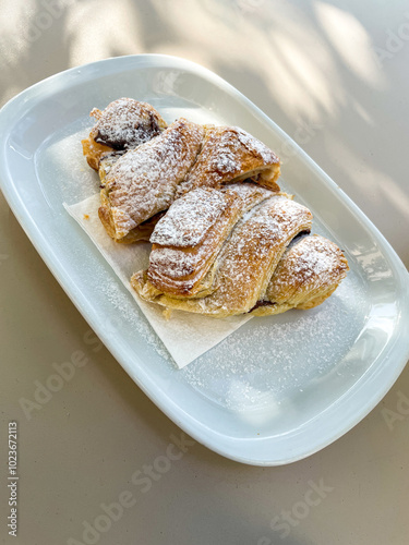 Delicious chocolate croissant on a sunlit terrace table at a cozy snack bar, perfect for breakfast or a sweet treat. Ideal for food photography and café lifestyle themes. photo