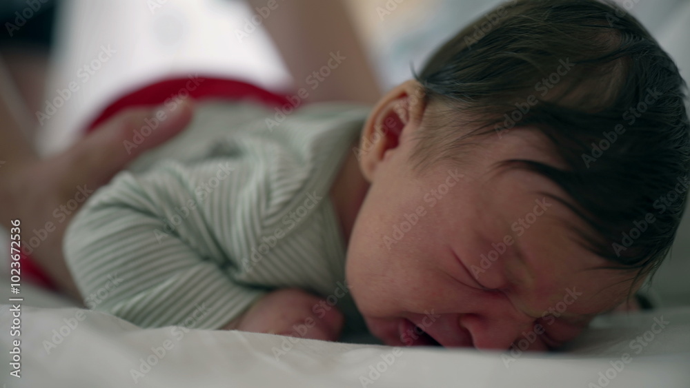 Mother gently picking up her crying newborn baby from the bed, soothing the distressed infant with a comforting touch, highlighting the nurturing care and close bond in a tender moment Mother gently picking up her crying newborn baby from the bed, soothing the distressed infant with a comforting touch, highlighting the nurturing care and close bond in a tender moment