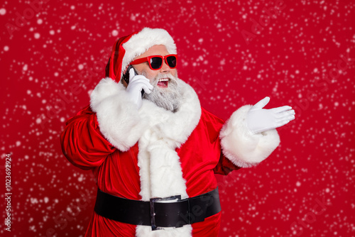 Portrait of attractive bearded cheery Santa calling using roaming talking contact isolated over bright red color background