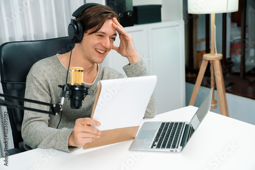 Host channel in smart broadcaster with talking show on live social media streaming with script note reading to listeners, wearing headphones to record video streamer at modern home studio. Pecuniary.