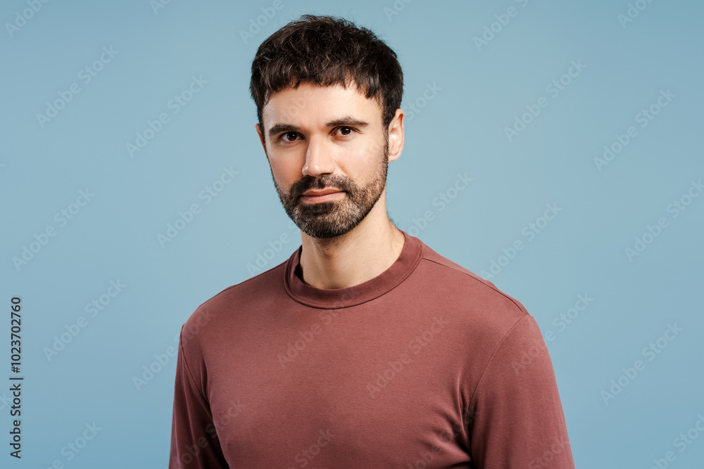 Portrait smiling bearded man wearing stylish sweater, looking at camera, isolated on blue background Portrait smiling bearded man wearing stylish sweater, looking at camera, isolated on blue background