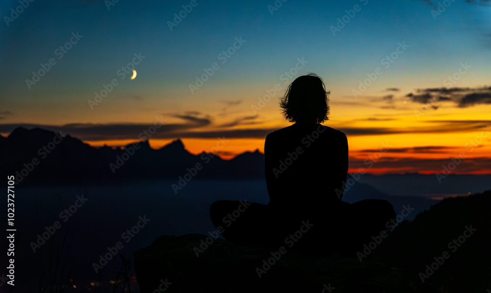 Yoga practitioner meditating in the Swiss Alps at sunset Yoga practitioner meditating in the Swiss Alps at sunset
