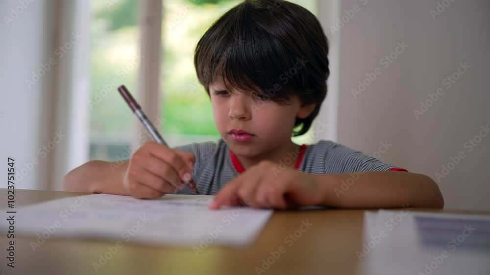Boy sketching carefully with a marker, leaning on the table while intently drawing on paper, focused on creating his artwork Boy sketching carefully with a marker, leaning on the table while intently drawing on paper, focused on creating his artwork