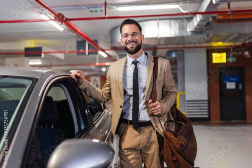 Portrait of young businessman standing next to his car in an underground garage