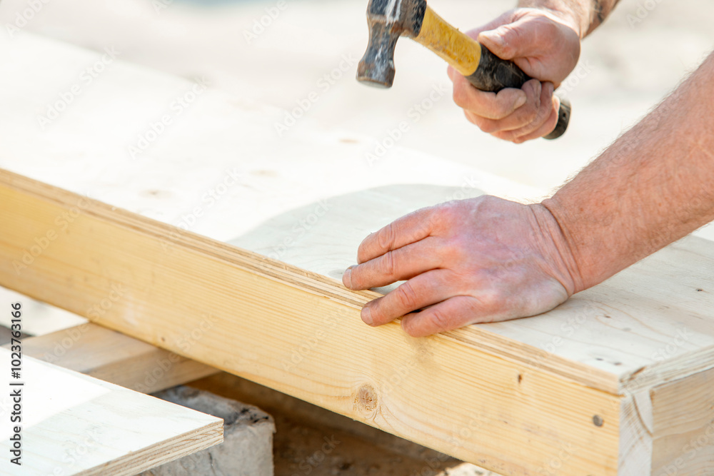 Joiner carpenter assembling formwork shutter. Crafting a wooden structure with precise hammer strikes at a sunny outdoor workshop in the afternoon Joiner carpenter assembling formwork shutter. Crafting a wooden structure with precise hammer strikes at a sunny outdoor workshop in the afternoon