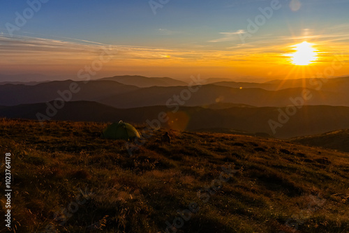 green tent on top of a mountain at sunset