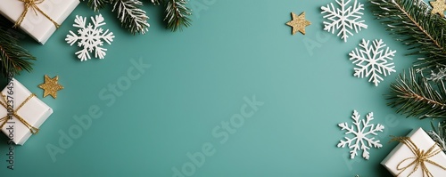 Minimalistic flat lay with elegant white snowflakes, gold stars, and fir branches scattered on a green background