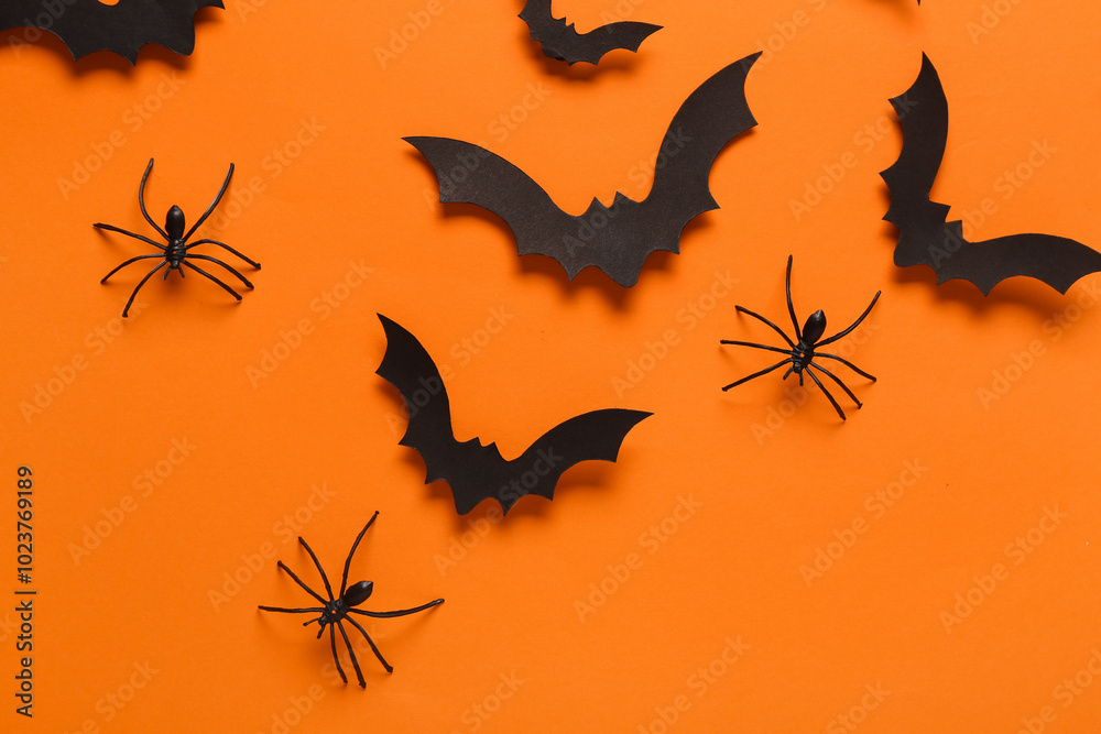 Paper bats and spiders for Halloween party on orange background Paper bats and spiders for Halloween party on orange background