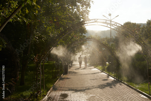 Street artificial air conditioning in hot weather. Walking path with pedestrians in cold fog. Comfortable walking. photo