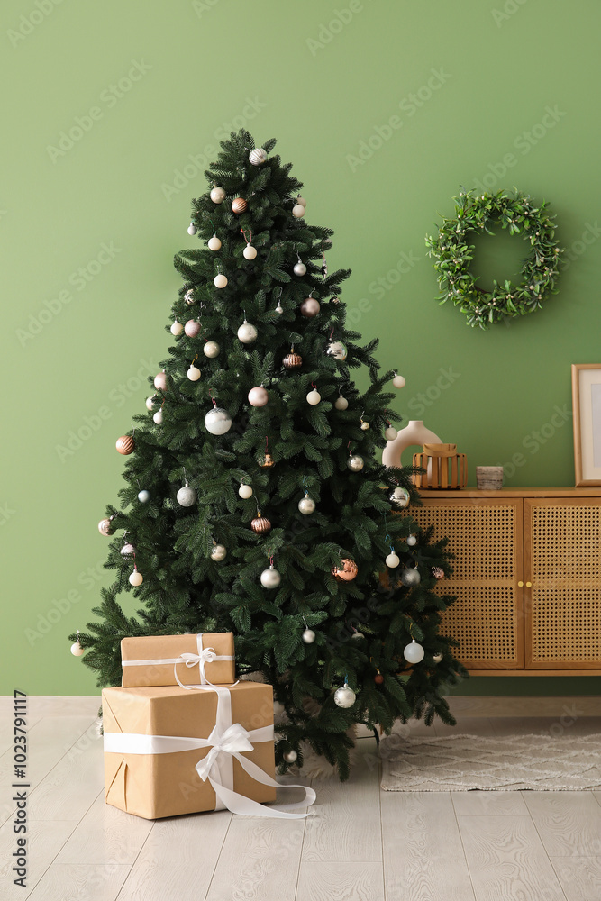Beautiful Christmas tree with gift boxes and dresser near green wall Beautiful Christmas tree with gift boxes and dresser near green wall