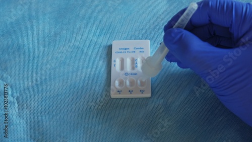 Medical Staff Member Using Quick Antigen Test Cassette for Covid 19 Flu and RSV Infection Dripping Drops from Pipette onto Chromatographic Immunoassay Material photo