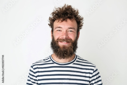 Happy young man in striped shirt with beard smiling.