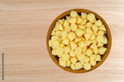 Overhead view of white baking chips in a bowl on a wood tabletop.