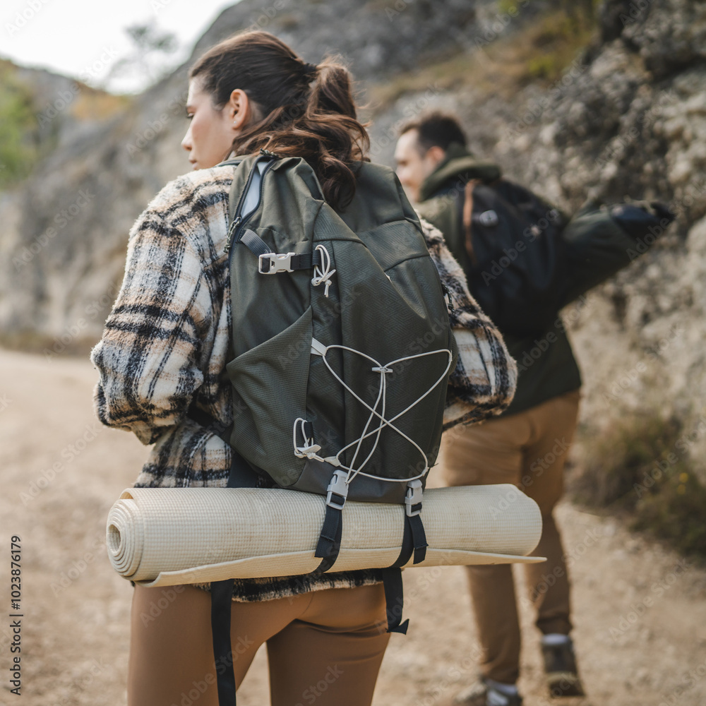 Fototapeta premium Back view of two backpackers hiking surrounded by nature