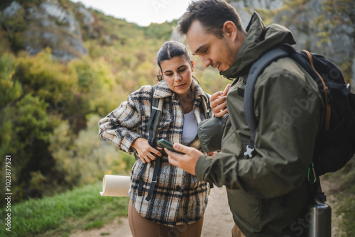 Boyfriend and girlfriend hikers explore forest with mobile phone