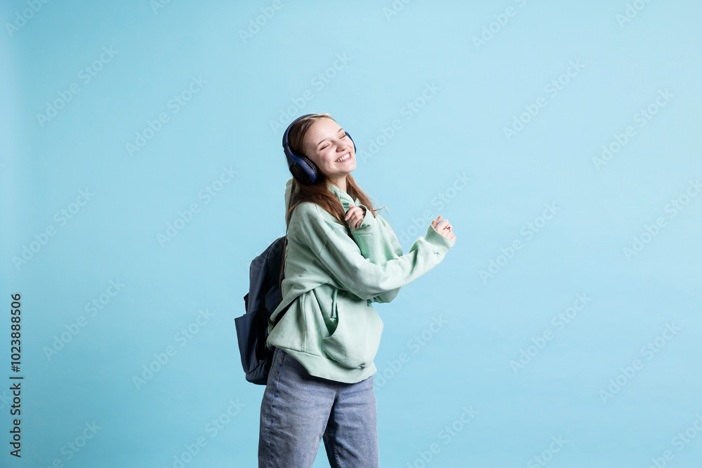 Jolly teenager having fun, dancing on rhythm, hearing songs in headphones, enjoying leisure time. Radiant person entertaining herself doing funky movements on music, studio background Jolly teenager having fun, dancing on rhythm, hearing songs in headphones, enjoying leisure time. Radiant person entertaining herself doing funky movements on music, studio background