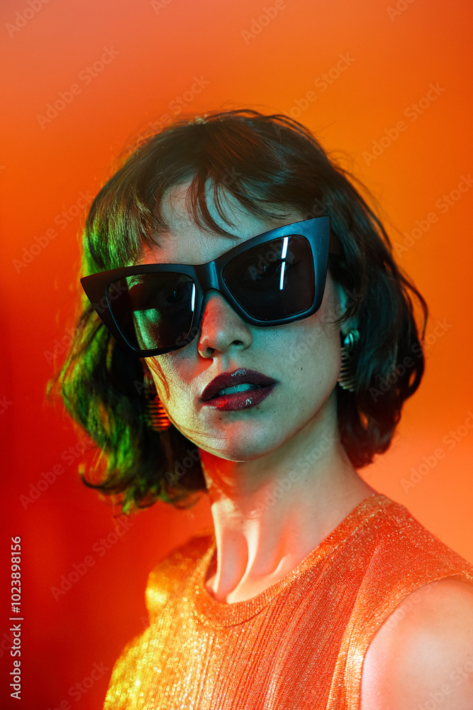 Woman in sunglasses against a vibrant orange background Woman in sunglasses against a vibrant orange background
