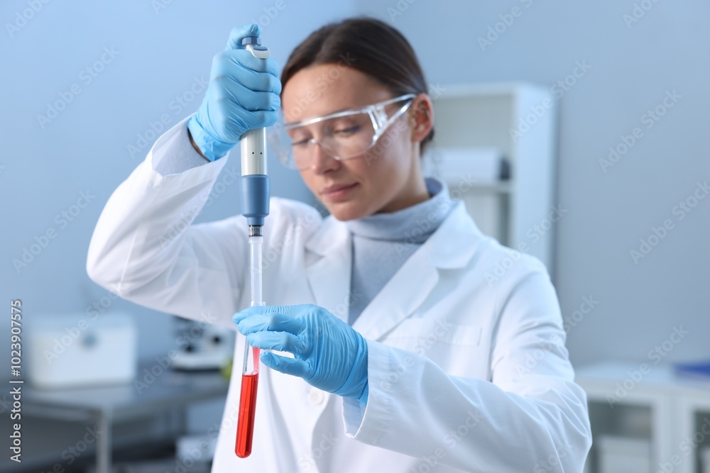 Naklejka premium Laboratory testing. Doctor dripping blood sample into test tube indoors
