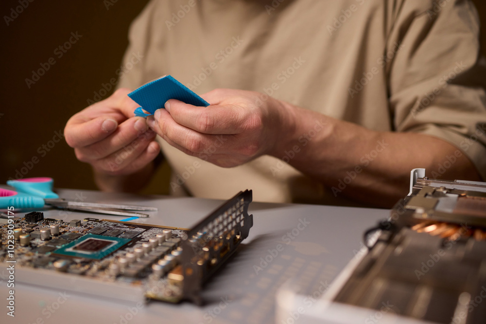 Fototapeta premium Hand Repairing a Graphics Card through the Application of Thermal Paste for Better Performance