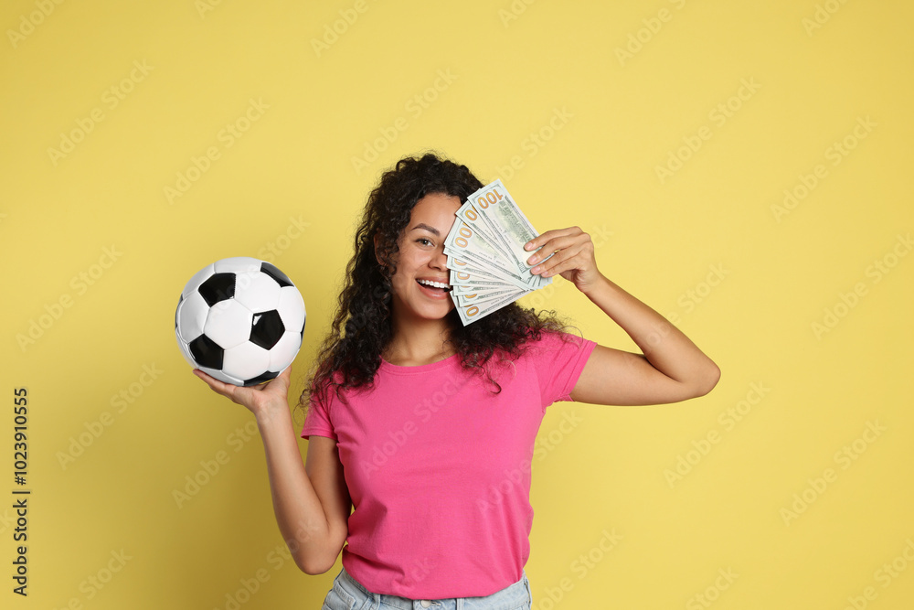 Happy woman with money and soccer ball on yellow background Happy woman with money and soccer ball on yellow background