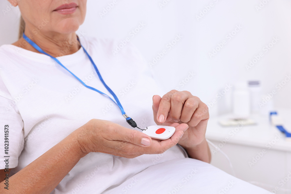 Obraz premium Senior woman with emergency call button on bed in hospital, closeup