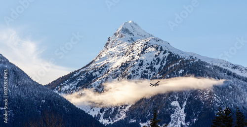 Scenic View of Airplane Flying Against Snow-Capped Mountains in Squamish, BC, Canada photo