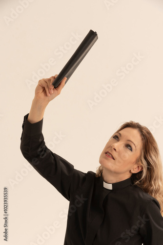 West Sussex England UK. 17.08.2024. Woman priest wearing a clerical collar  and hand out stretched holding a black book. photo