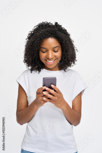 Young happy African gen z model standing isolated on white background looking at smartphone. Smiling Afro American woman using mobile cell phone advertising online shopping applications. Vertical