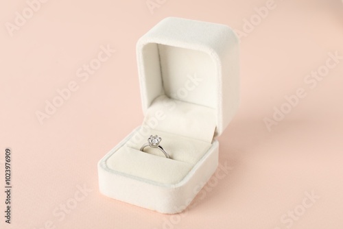 Beautiful ring with gemstone in box on pink background, closeup