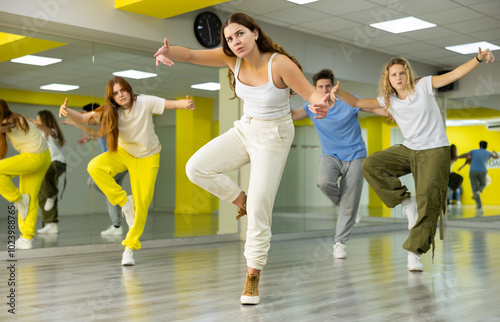 Portrait of expressive teens dancer in choreographic studio with dancing teenagers in background photo