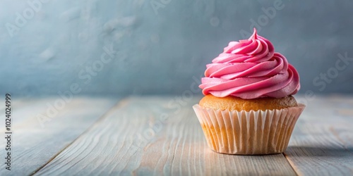 A cupcake with pink frosting on a table, topped with a generous amount of creamy frosting, cupcake, pink, frosting