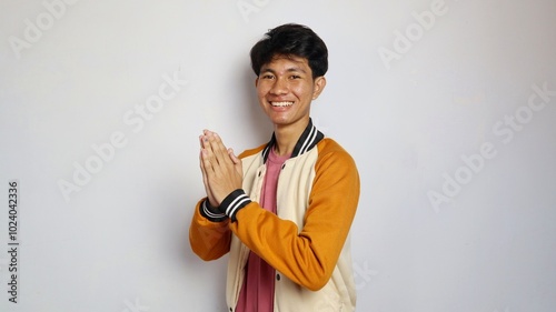 casual excited young handsome Asian man giving a greeting gesture photo