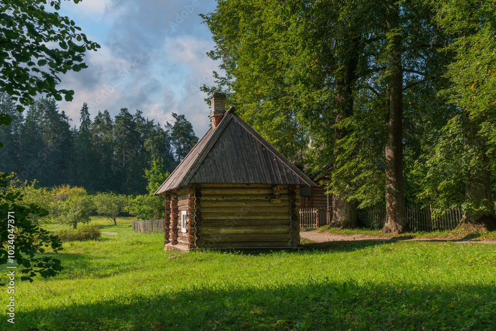 View of the traditional log Russian house in the Mikhailovskoye estate of the Pushkin Museum-Reserve on a sunny summer day, Pushkinskiye Gory, Pskov region, Russia View of the traditional log Russian house in the Mikhailovskoye estate of the Pushkin Museum-Reserve on a sunny summer day, Pushkinskiye Gory, Pskov region, Russia
