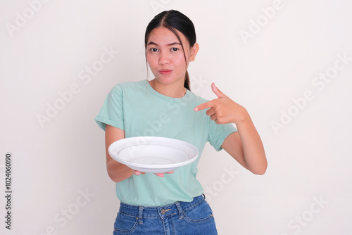 A woman pointing at empty dinning plate that she hold with excited expression photo