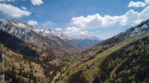 Majestic Mountain Range Under Bright Sky and White Clouds. A breathtaking view of a snow-capped mountain range with vibrant green valleys, showcasing nature’s stunning beauty and tranquility. photo
