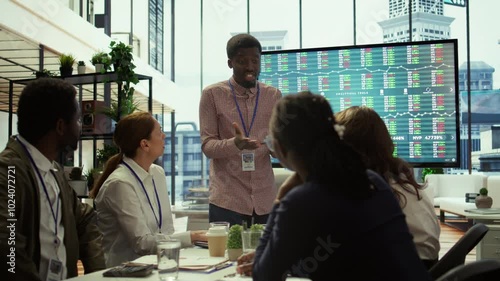 Manager briefs team on corporate collapse revealing bankruptcy and insolvency. CEO presents troubling financial data, signaling the end of the company and loss of jobs for all staff. Camera B.