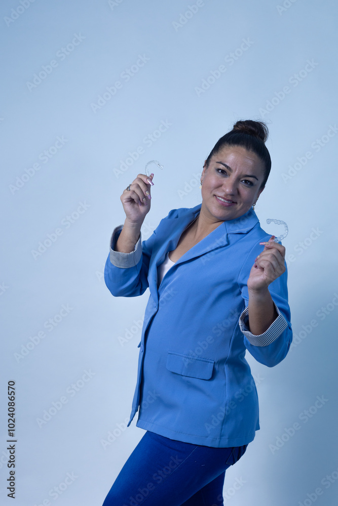 Woman posing with dental aligners, wearing blue suit Woman posing with dental aligners, wearing blue suit