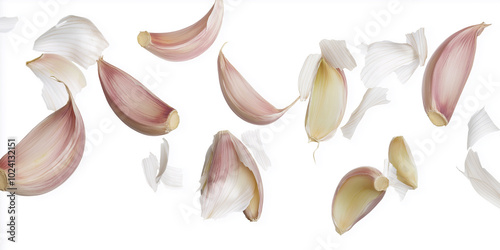 Garlic cloves and peel flying on white background