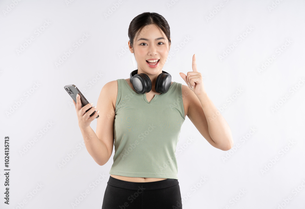 Portrait of young Asian girl wearing sports clothes, wearing headphones and using phone Portrait of young Asian girl wearing sports clothes, wearing headphones and using phone