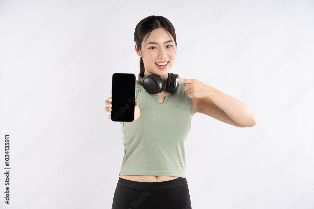 Portrait of young Asian girl wearing sports clothes, wearing headphones and using phone