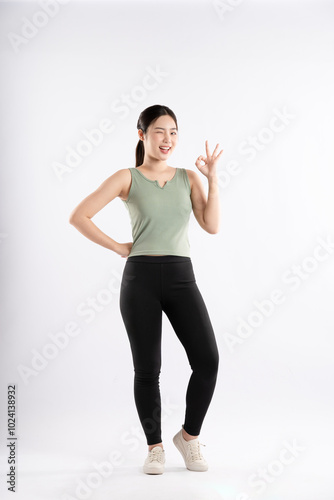 Full body image of young Asian girl wearing sports outfit and posing on white background