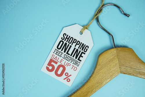 Shopping Online Sale up to 50% on price tag with wooden clothes hanger top view on blue background, business and promotion concep photo