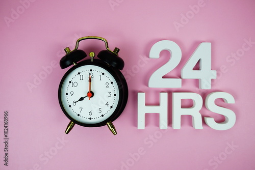 24 Hrs alphabet letters and alarm clock top view on pink background photo