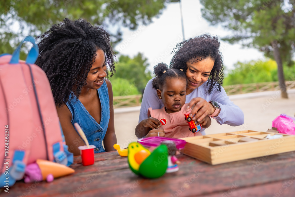 African grandmother and mother playing with girl in a park African grandmother and mother playing with girl in a park
