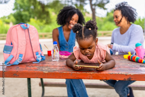 African girl using mobile phone in the park with family