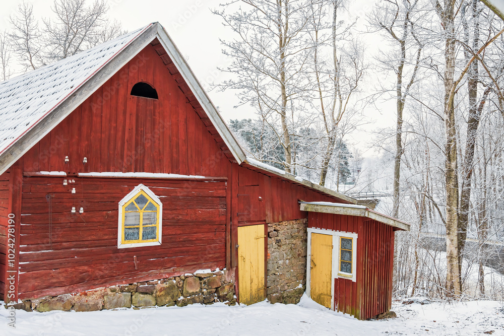 Old red barn with a outhouse in a wintry landscape