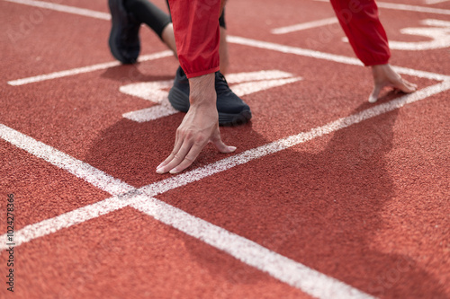 Cool Asian guy wearing red exercise clothes. Starting out on the running lane in the stadium. Both hands are placed on the floor close to the body. outdoor exercise maintaining health active living