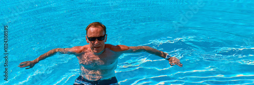 Tanned athletic middle aged european man posing in pool water on summer afternoon