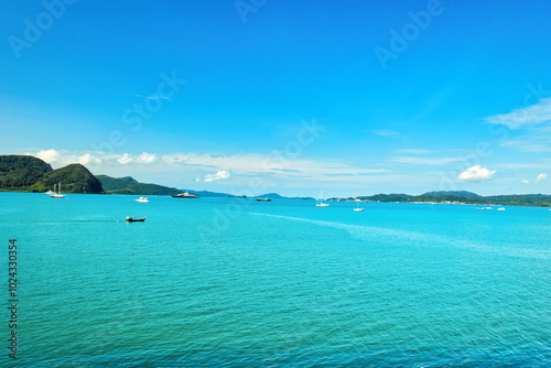 A beautiful view of Langkawi island against a beautiful blue sky with some boats in the distance on the horizon. Tropical scenery. located at Kedah, Malaysia - September 25 2024: