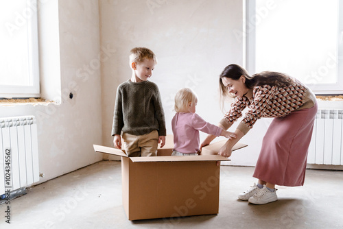 A young woman rides her children in a box, house where construction photo